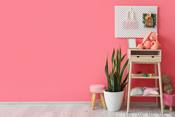 Interior of stylish children's room with stand-up table, houseplant and pegboard