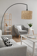 Interior of light living room with standard lamp, sofa and armchair