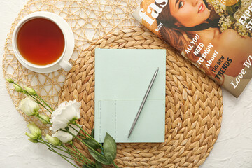 Beautiful composition with notebook, cup of tea, magazine and flowers on white background