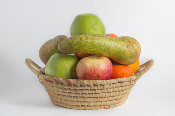 baskets with pears, apples, oranges and tangerines on wood and white background