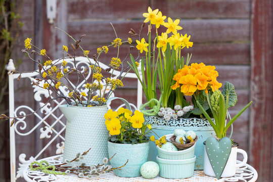 Osterdekoration mit gelben Fr&uuml;hlingsblumen in vintage Gef&auml;&szlig;en und Ostereiern im Garten