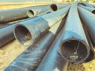 construction of a sewerage system in a new microdistrict. black rubber pipes lie on the sand at the...