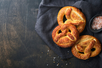 Bavarian pretzels and glass of lager beer. Oktoberfest food menu, traditional salted pretzels over old dark wooden background. Top view with space for text. Oktoberfest theme