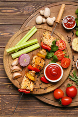 Boards of grilled chicken skewer with vegetables and sauce on wooden background