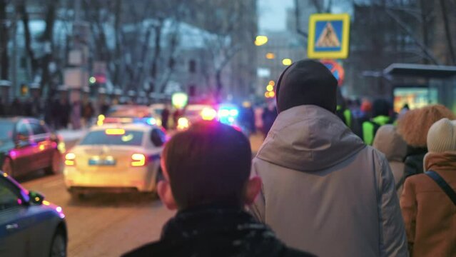 Protesting Russian people on crowded streets of Moscow. Political demonstration activists walk under police car flash bar, flasher strobe. Protesters in Russia picket rally march with flashing lights.