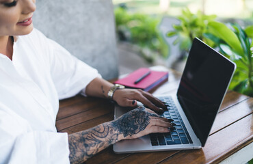 Cropped female IT professional browsing web page on modern laptop computer using 4g wireless connection at cafe terrace, skilled blogger creating text content and graphic design via app on netbook