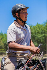 Fototapeta premium young latin male rider, mounted on top of a horse looking at the horizon. vertical photo