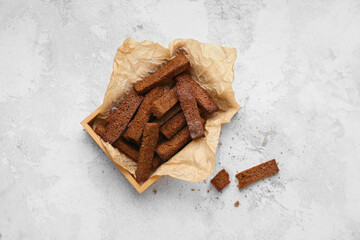 Wooden box with rye croutons on light background