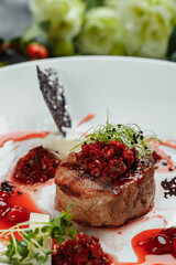 Appetizing beef in sweet sauce close up. Chopped beef meat in cherry sauce with vegetables on plate. Delicious european cuisine