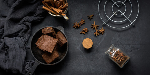 pieces of baked brownie in a metal black frying pan on the table, top view