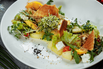 Summer diet salad with leaves of lettuce, watermelon, peach and feta cheese. On a light blue background copy space