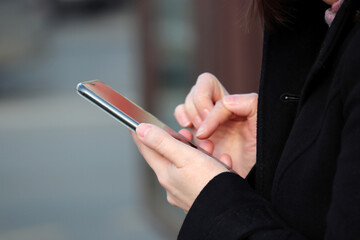 Female hands with smartphone close up. Woman using mobile phone on a city street