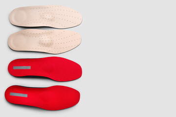 Two pairs of orthopedic insoles on grey background