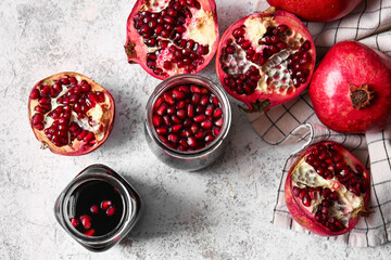Jars of pomegranate molasses and fresh fruits on light background