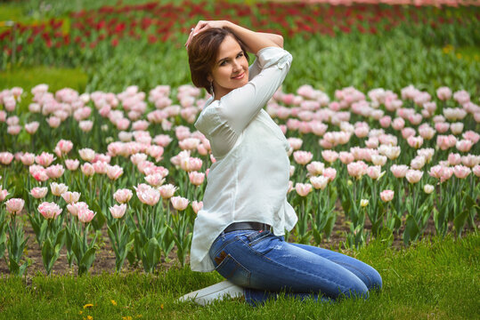 A series of photos with a beautiful young girl who walks in a spring garden with many colorful tulips
