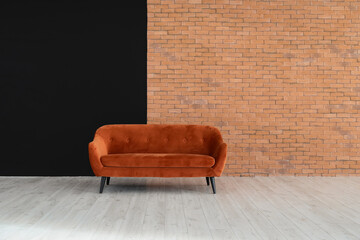 Red sofa near black and brick wall in big empty room