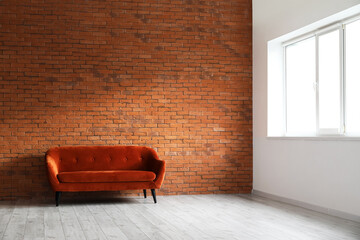 Red sofa near brick wall in empty room