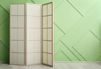 Stylish folding screen near color wall in room