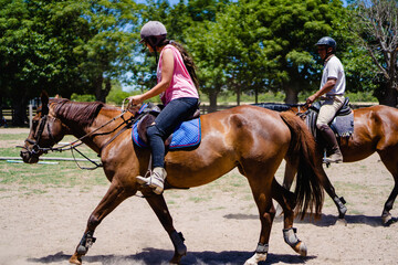 couple practicing horseback riding together, instructor at the rear