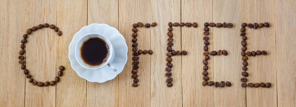 Inscription "COFFEE". Composition of coffee beans and a cup of coffee on a wooden background