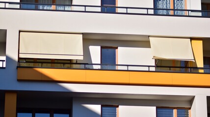 Modern architecture building facade with awnings. Balcony with awning opened, covered by sun-shield. 