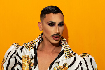 Portrait of beautiful drag queen with piercing eyes on yellow background