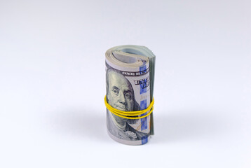 Money roll tightened with rubber band on white background. Rolled US dollars