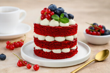 Mini red velvet cake decorated with berries and mint. Portion cake on a white plate with a cup of tea. selective focus 