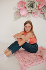 Obraz na płótnie Canvas Beautiful teen girl in jeans and pink top. Photo shoot in pink paper flowers and pink pillow