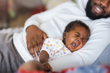 Father holding his baby in arms at home
