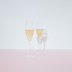 Two glasses with white wine on pastel pink and white background. Wine drinking culture concept. Apperetes and survivors. Copy space.