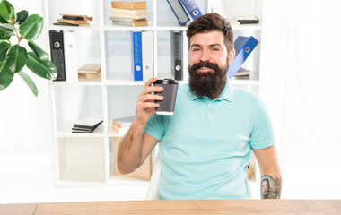 Fototapeta premium Happy man holding takeaway coffee cup sitting in office, coffee break