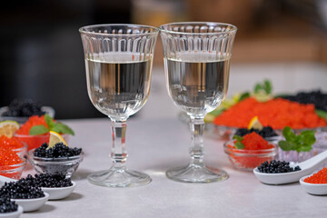 Caviar and two glass with white wine or champagne. Tasting salmon red caviar and black beluga sturgeon salted roe. Set of delicious snacks on tasting table on banquet. Expensive delicacy