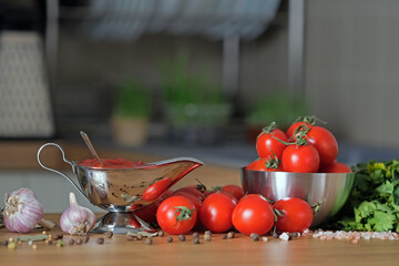 Vegetarian Ketchup in sauceboat on black background, fresh tomatoes, garlic, pepper and spice near. Delicious vegetarian sauce. Cooking marinara from raw cherry tomato. Food backdrop
