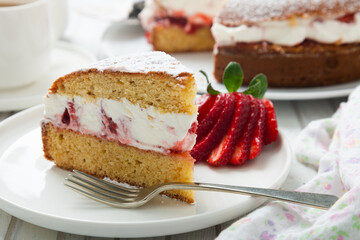 Victoria sponge cake filled with whipped cream, jam and fresh strawberries in a dish