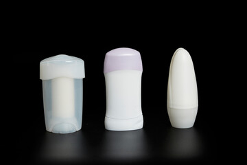 Three unmarked bottles of deodorant on black background with reflection underneath.