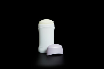 Non-branded deodorant stick. Transparent white bottle with lid set on black background and with...