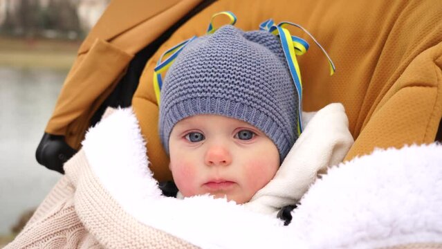 Little Ukrainian girl on the street with yellow-blue ribbons, Ukrainian flag