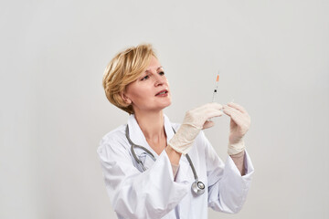 Focused female doctor hold and look at syringe
