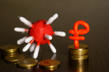 A virus figurine with coins on the table. Next to the ruble sign.