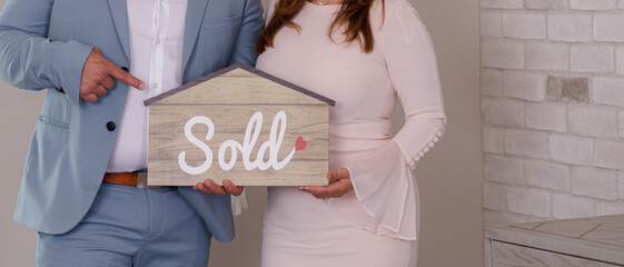 person holding a sold sign in the shape of a house real-estate agent  