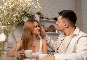 Married couple sitting at kitchen table, drinking tea or coffee, looking at each other with love and tenderness. Romantic family relationship concept. High quality photo