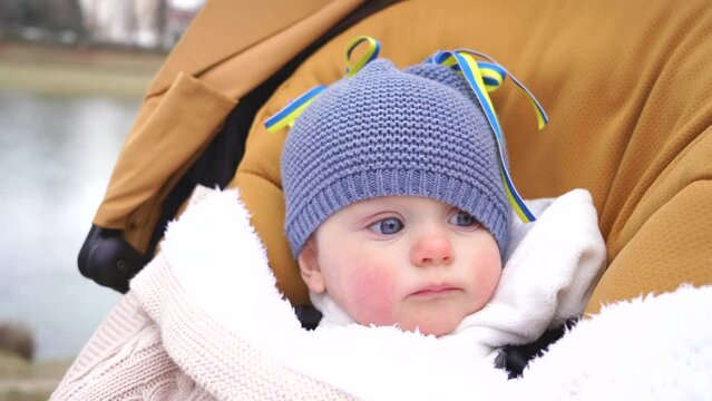Little Ukrainian girl on the street with yellow-blue ribbons, Ukrainian flag