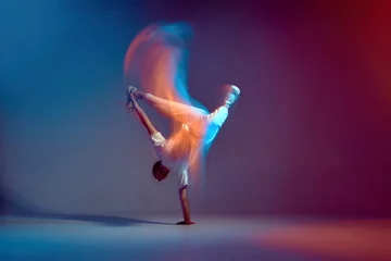 Fotobehang Dansschool Cool jonge breakdancer dansen hiphop in neon studiolicht, staande bij de hand. Dansschool reclame. Lange blootstelling