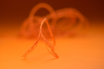 A torn rope with an uneven end. Orange rope on orange background.