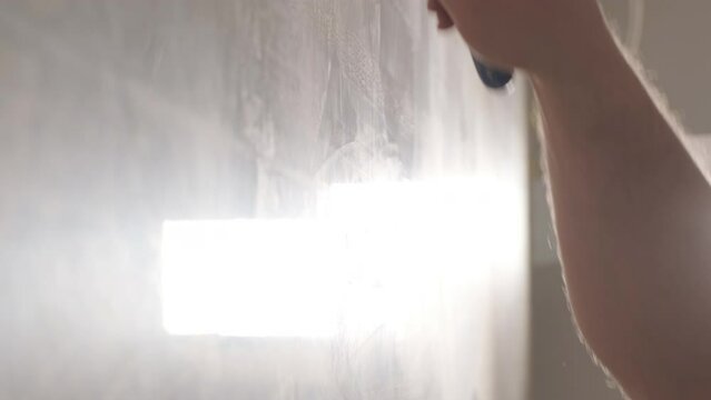 Man plastering the walls with finishing putty in room with putty spatula