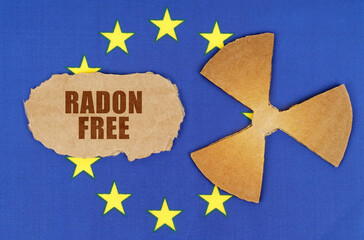 On the flag of the European Union, the symbol of radioactivity and torn cardboard with the inscription - RADON FREE