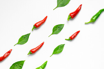 Hot red and green fresh chili peppers, green leaves on white background flat lay top view....