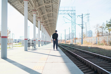 single lonely man standing on the train station and waiting for the next train trip