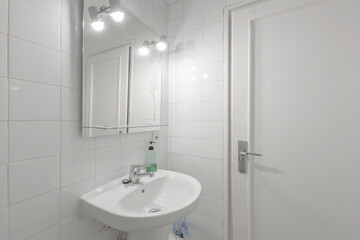 Fototapeta na wymiar Toilet with glass shower stall, white porcelain sink in vacation rental apartment